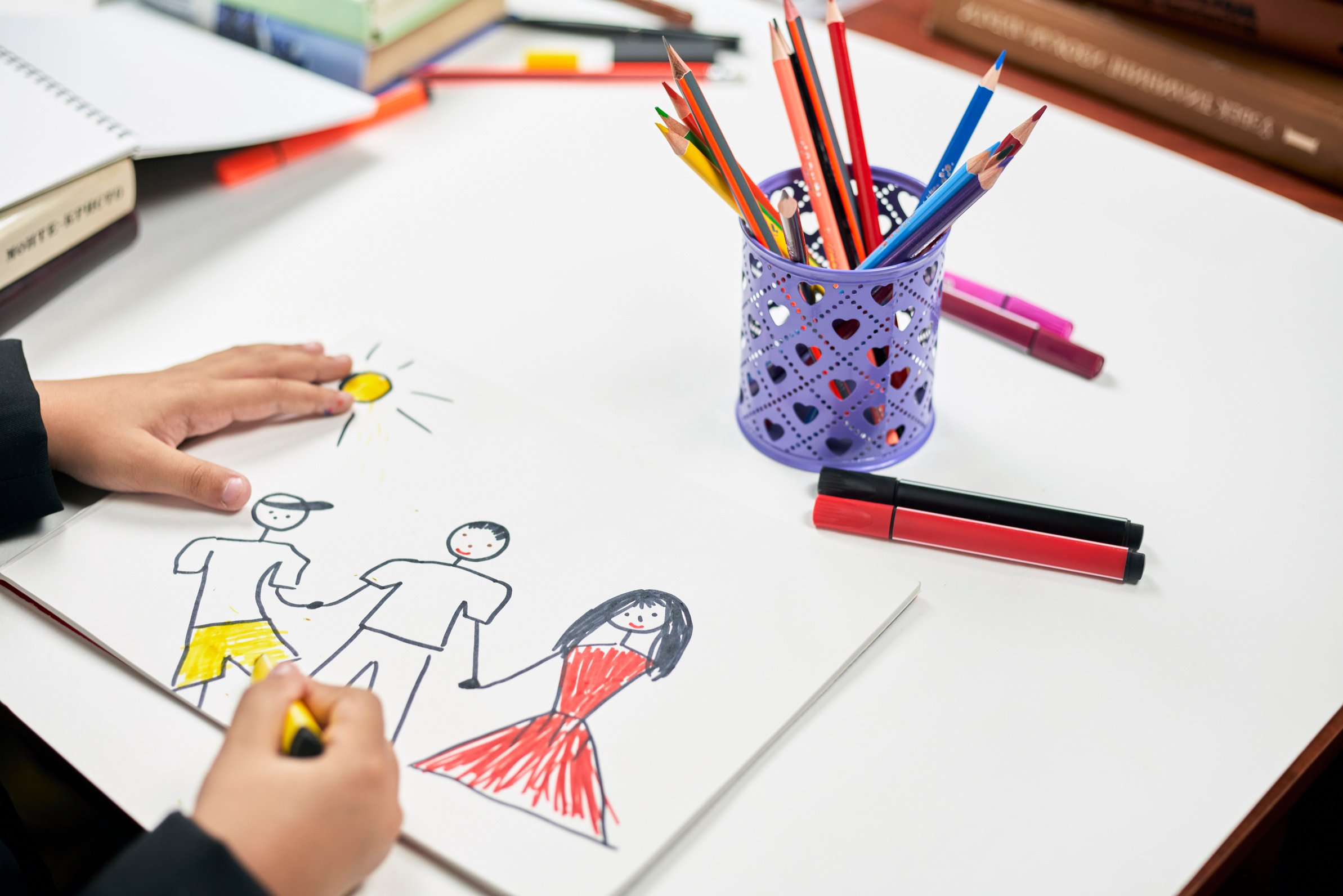 Family therapy. Schoolboy drawing family. Painting with colored marker